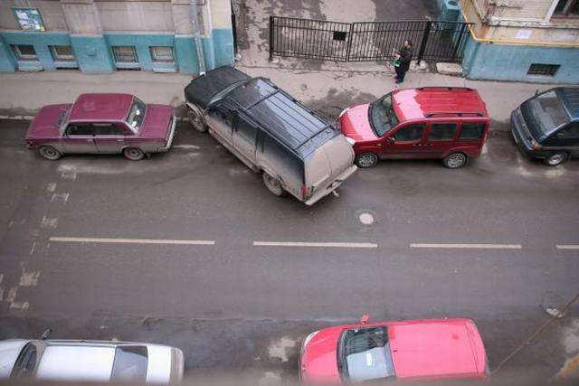 Vemos tres carros dos estan bien parquedos y otro que se entra entre los dos